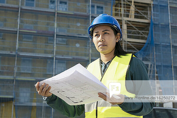 Frau hält Bauplan auf einer Baustelle