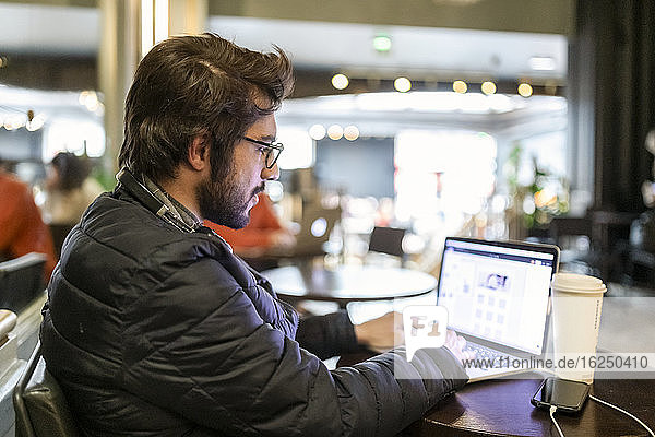 Mann benutzt Laptop in einem Cafe