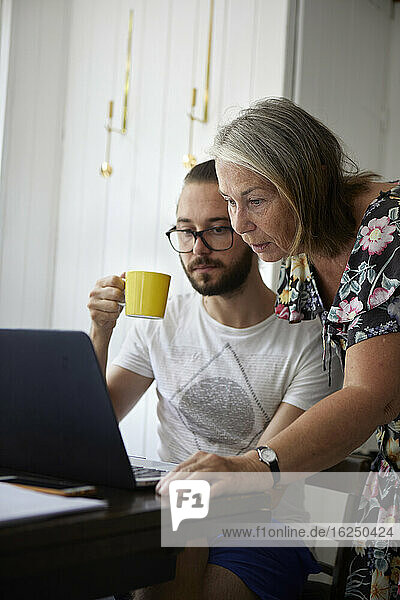 Ältere Frau benutzt Laptop mit erwachsenem Sohn