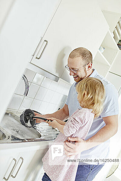 Vater und Tochter beim Geschirrspülen