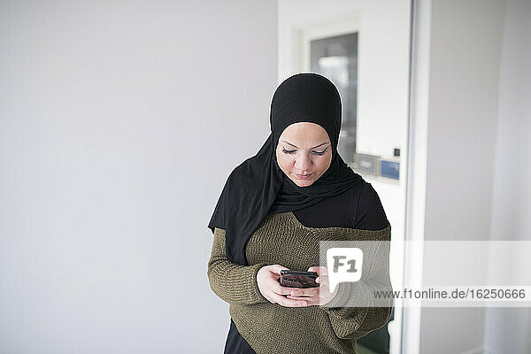 Junge Frau benutzt Smartphone im Büro