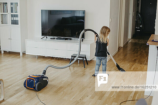 Girl vacuum cleaning living room