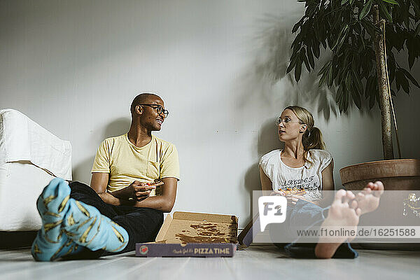 Couple sitting on floor and having pizza