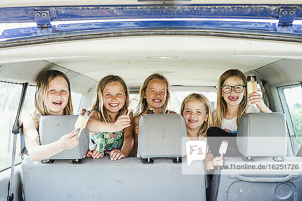 Happy girls in car holding ice lollies