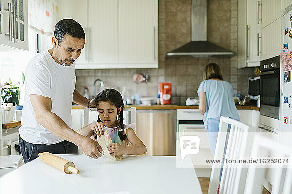Father helping daughter with dough