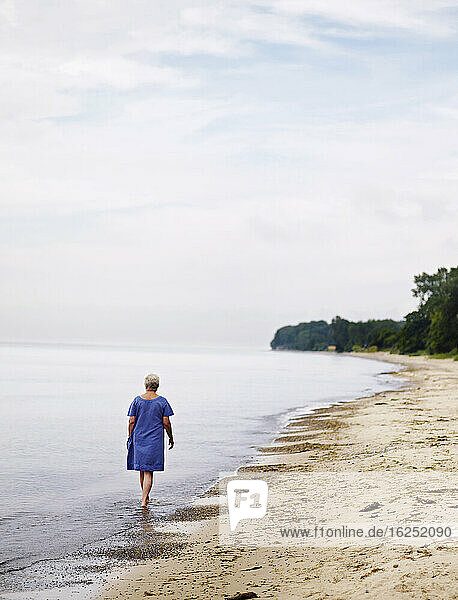 Elderly woman walks in waterfront by beach