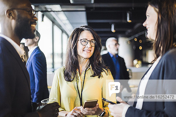 Lächelnde Unternehmerinnen stehen mit einem männlichen Kollegen im Amt