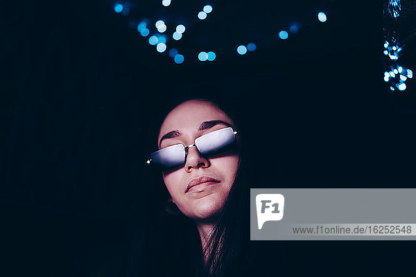 Selbstbewusste junge Frau mit Sonnenbrille im beleuchteten Restaurant