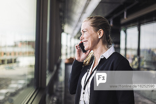Smiling entrepreneur talking on mobile phone while standing at workplace