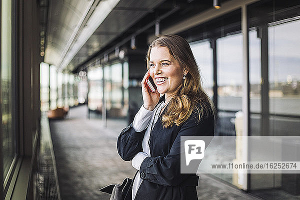Lächelnde Geschäftsfrau telefoniert im Stehen am Arbeitsplatz