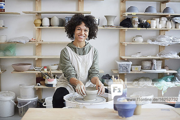 Portrait of smiling woman learning pottery in art studio
