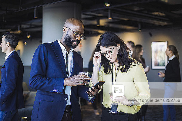 Male entrepreneur showing smart phone to female colleague in office