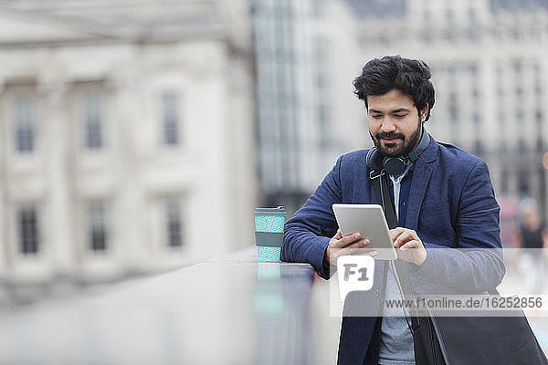 Geschäftsmann benutzt digitales Tablett auf Stadtbrücke