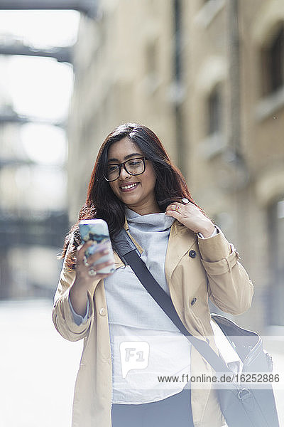 Smiling businesswoman using smart phone on street