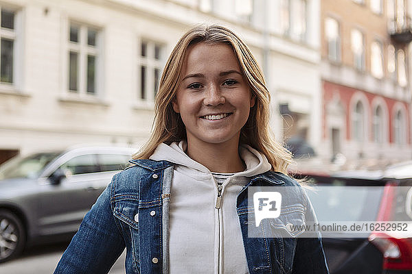 Porträt einer glücklichen Teenagerin  die am Wochenende in der Stadt steht