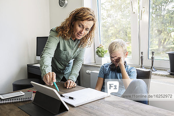 Mutter unterrichtet Sohn zu Hause auf digitalem Tablett