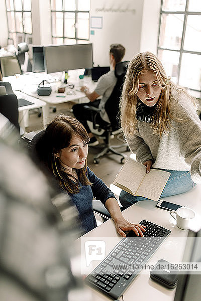 Berufstätige Frauen diskutieren bei der Arbeit am Computer am Arbeitsplatz