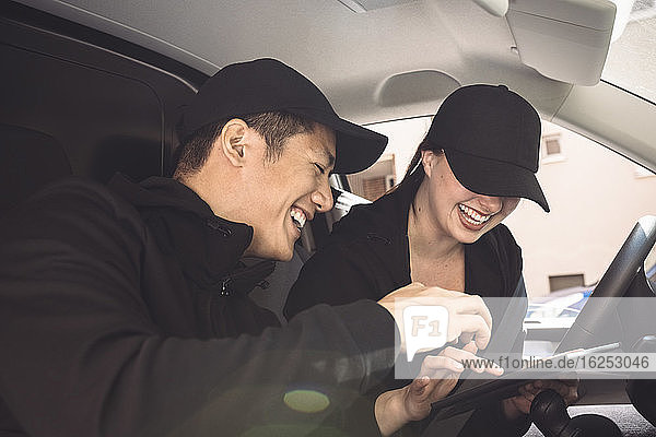 Lächelnde männliche und weibliche Fahrer mit digitalem Tablet im Lkw