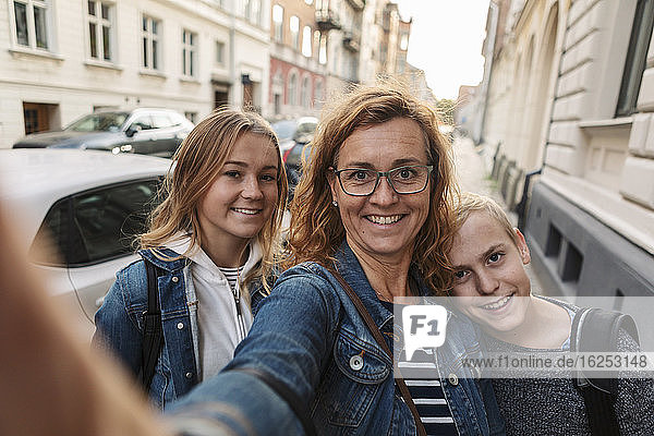 Porträt einer lächelnden Mutter und von Kindern  die am Wochenende am Straßenrand Selbstmord begehen