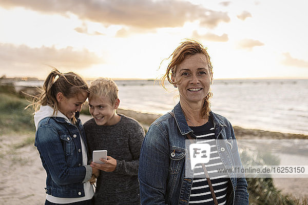 Porträt einer lächelnden Mutter mit Kindern am Strand