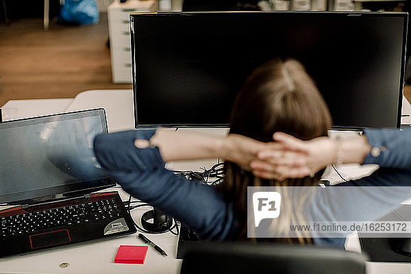 Rückansicht eines Unternehmers  der gegen einen Computer im Büro sitzt