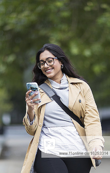 Lächelnde Frau geht mit Smartphone