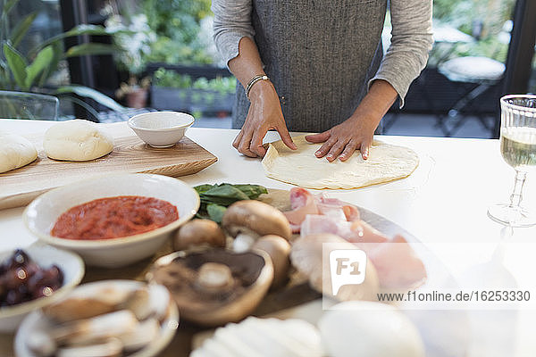 Woman making fresh homemade pizza in kitchen