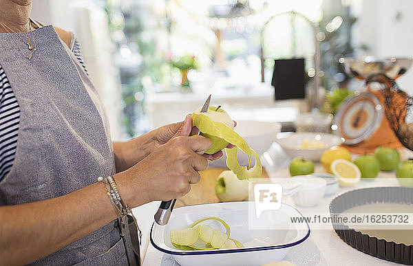 Nahaufnahme einer Frau  die in der Küche grüne Äpfel für Kuchen schneidet