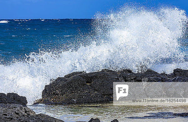 Waves crashing and splashing on lava rock along the shore of Kaupo Cove; Oahu  Hawaii  United States of America