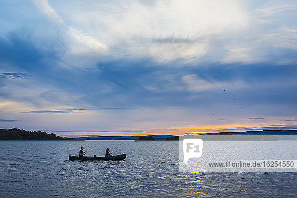 Mann und Frau paddeln bei Sonnenuntergang auf dem See Lough Derg mit einem Kanu; Grafschaft Clare  Irland