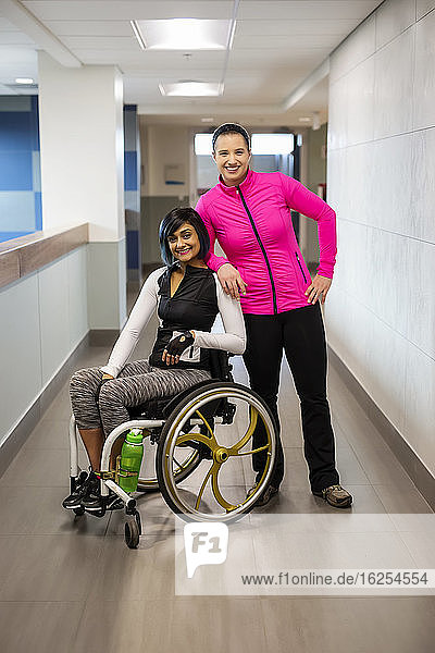 A paraplegic woman and her trainer pose for the camera while in a hallway in a recreational facility: Sherwood Park  Alberta  Canada