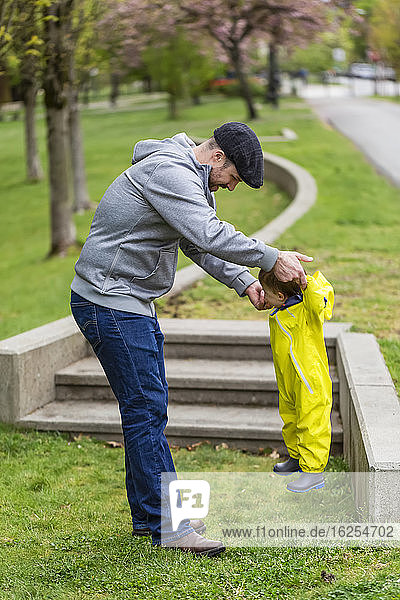 Vater spielt an einem Frühlingstag mit seiner Tochter im Park und hebt sie mit den Händen in die Luft; Surrey  Britisch-Kolumbien  Kanada