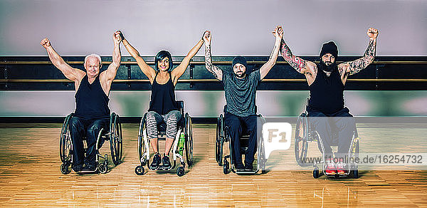 Eine Gruppe querschnittsgelähmter Freunde hebt nach einem Training in einer Fitnesseinrichtung gemeinsam die Hand zum Sieg: Sherwood Park  Alberta  Kanada