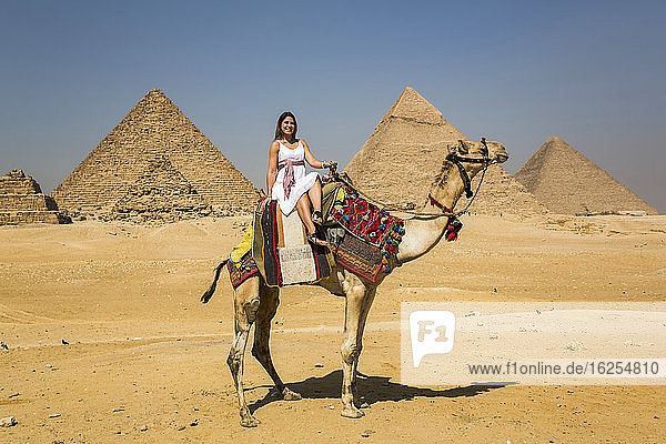 Weibliche Touristin auf einem Kamel  Pyramidenkomplex von Gizeh  UNESCO-Weltkulturerbe; Gizeh  Ägypten