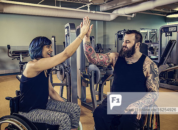 Zwei querschnittsgelähmte Freunde  die sich nach dem Training in einer Fitnesseinrichtung gegenseitig ein High Five geben: Sherwood Park  Alberta  Kanada
