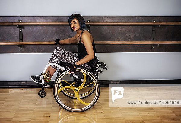 Eine querschnittsgelähmte Frau  die nach dem Training in einer Fitnesseinrichtung in ihrem Rollstuhl auf dem Rollstuhl sitzt und in einer Turnhalle herumtollt: Sherwood Park  Alberta  Kanada