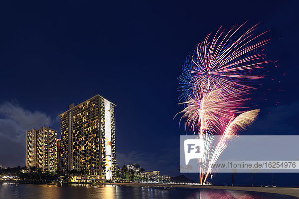 Eigentumswohnungen und Feuerwerk entlang der Küste von Waikiki bei Sonnenuntergang; Honolulu  Oahu  Hawaii  Vereinigte Staaten von Amerika
