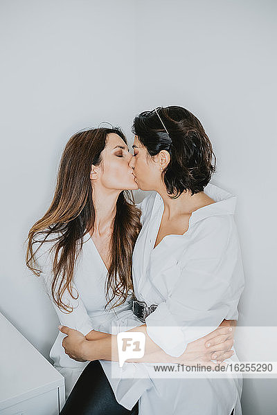 Porträt von zwei Frauen mit braunem Haar  die sich umarmen und küssen.