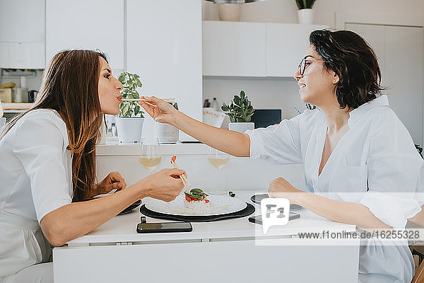 Zwei Frauen mit braunem Haar sitzen an einem Tisch und essen Sushi.
