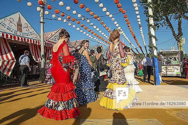 Frauen in bunten Flamencokleidern  vor Festzelten  Casetas  geschmückte Straße  Feria de Abril  Sevilla  Andalusien  Spanien  Europa