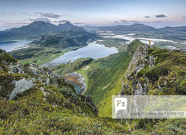 Tiny person stands at the summit and looks out over the vastness of the Lofoten mountains  Offersoykammen  Vestvågøy  Lofoten  Nordland  Norway  Europe