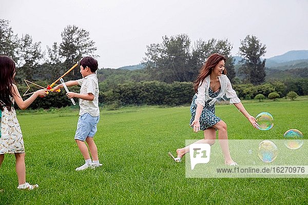 Mutter mit zwei Kindern  die auf dem Rasen spielen