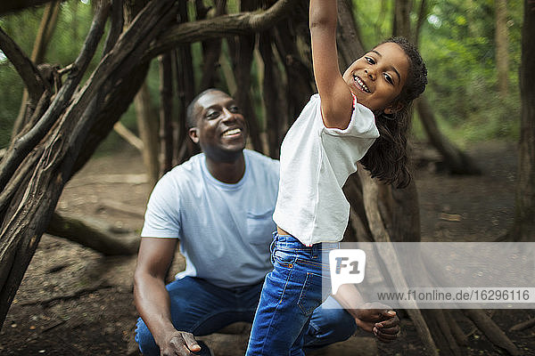Portrait happy father and daughter playing at tree in woods