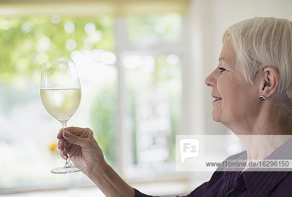 Ältere Frau trinkt Weißwein