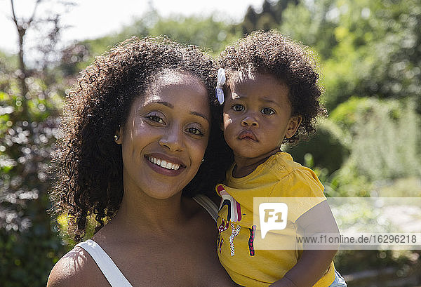 Portrait happy mother and toddler daughter in sunny yard