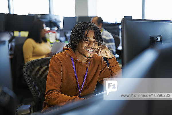 Lächelnder Geschäftsmann arbeitet am Computer im Büro