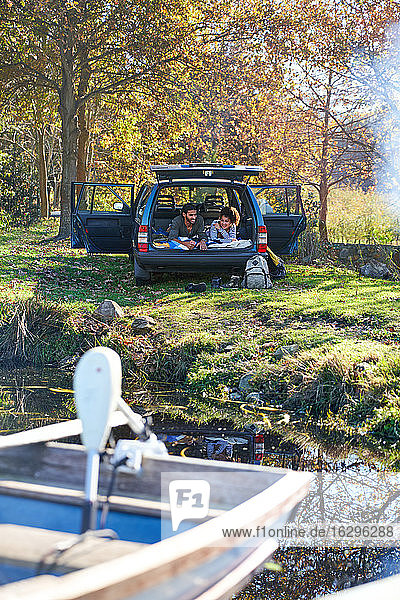 Junges Paar entspannt im Auto am sonnigen Herbstufer des Sees