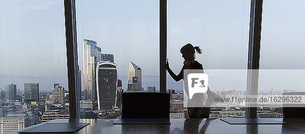 Geschäftsfrau streckt sich am Fenster eines Hochhausbüros  London  UK