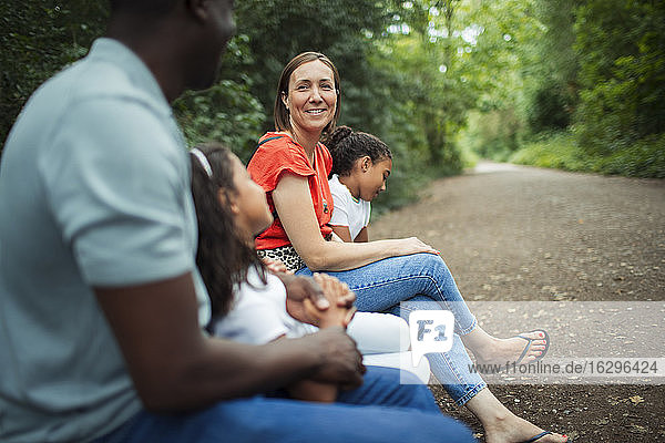 Happy family sitting on bench on path in park