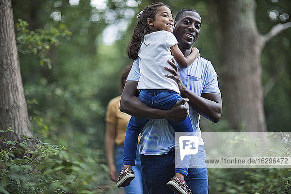 Happy father carrying daughter on hike in woods